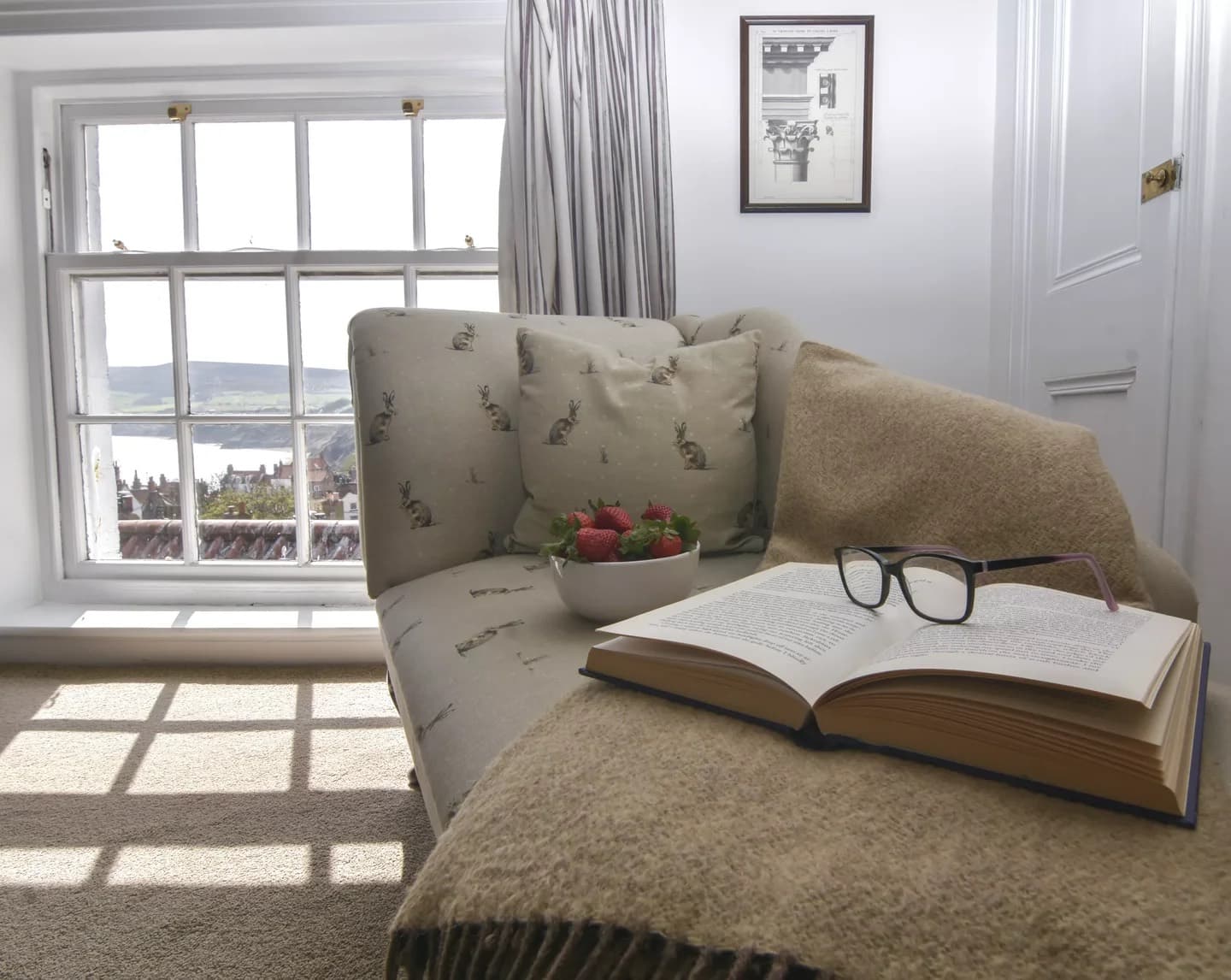 A book and strawberries on a window seat overlooking the bay