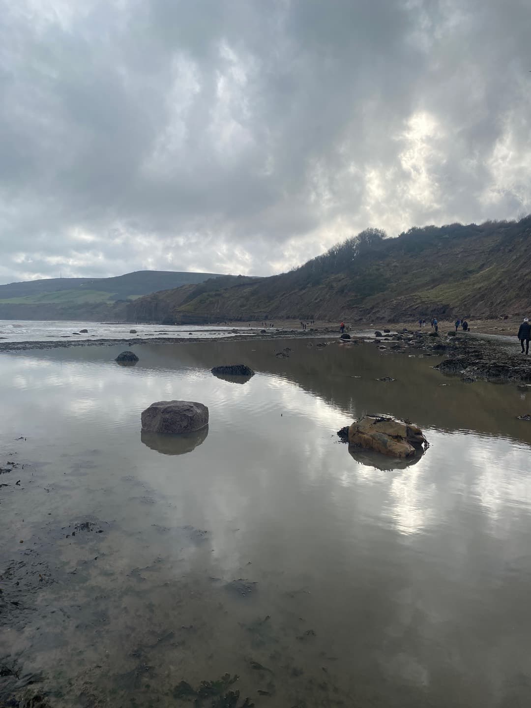 Clouds reflected around shoreline rocks