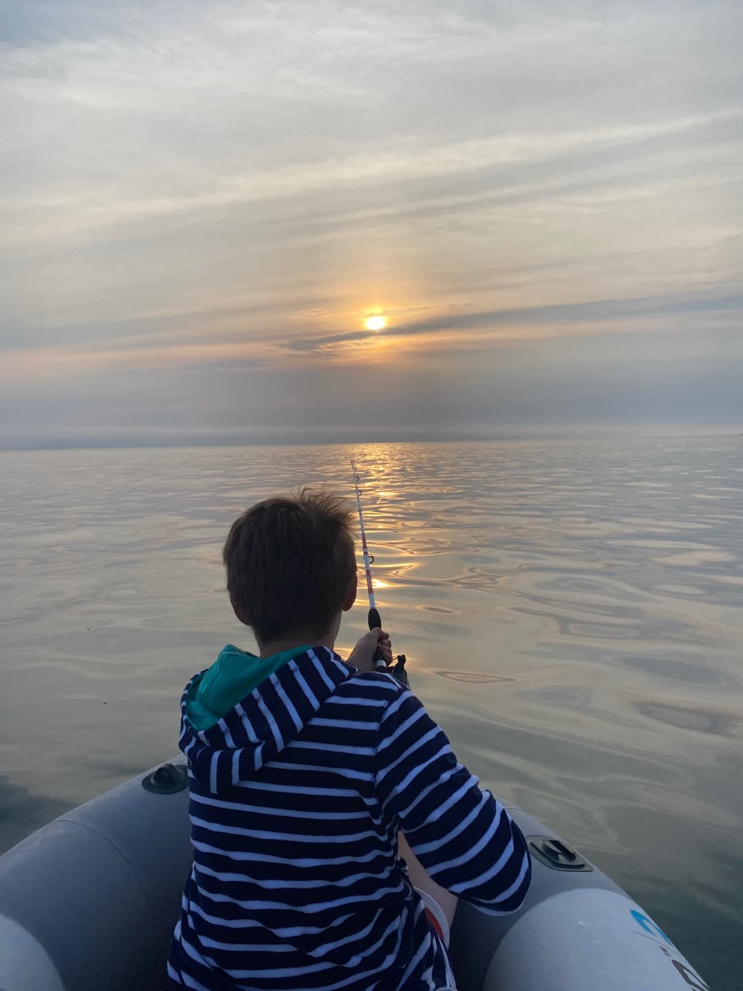 A person in a boat looking towards the sunset
